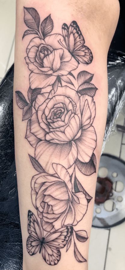 Fine-line roses running down a forearm, by Momo